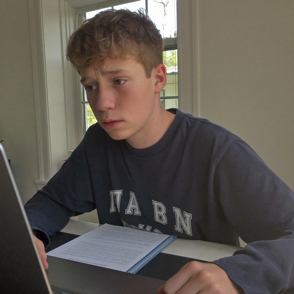 Teen boy looking uncertain at his laptop, having relied on AI for an essay